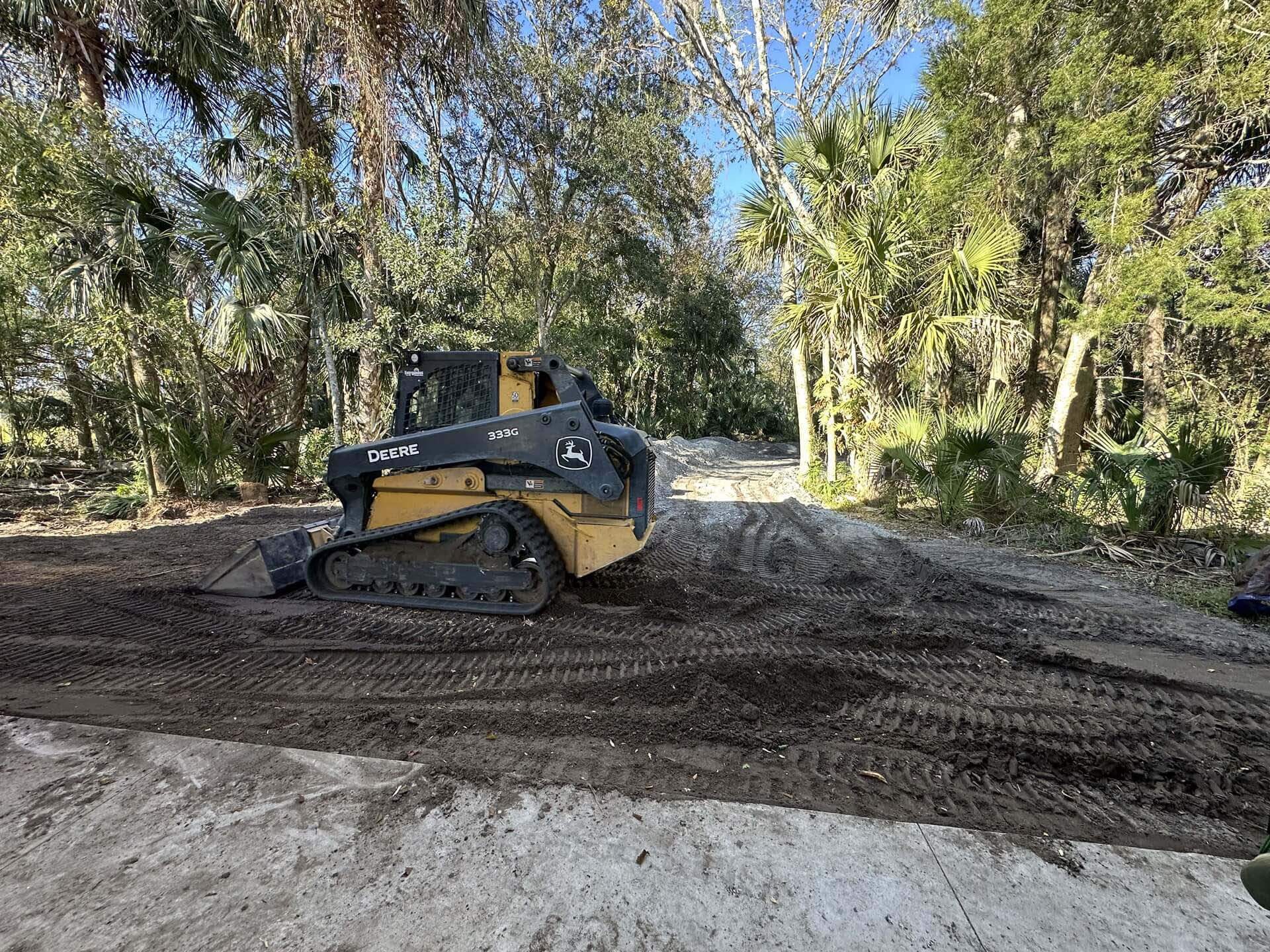 A skid-steer loader clearing an expansive wooded area.